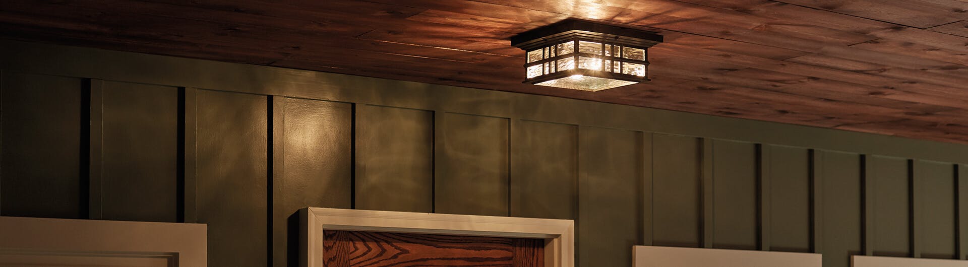 Exterior ceiling lit by the warm glow of a Beacon Sqaure flush mount light in olde bronze 