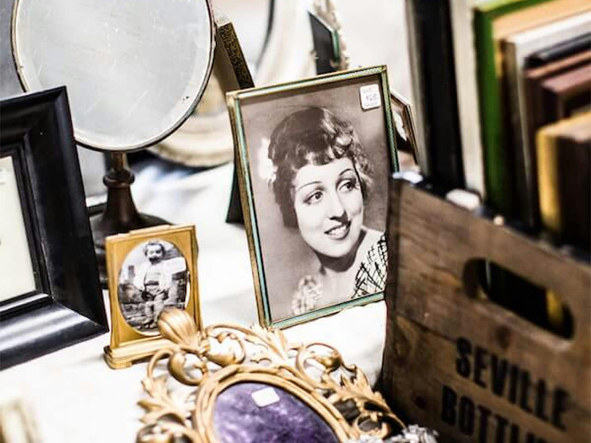 A lifestyle shot of vintage framed photos, hand held mirrors, and books 